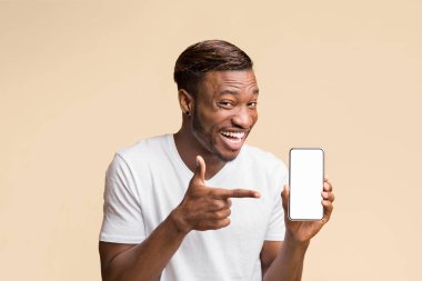 Sarı arka planda duran kameraya gülümseyen, elinde boş ekranla akıllı telefonu işaret eden Afro Adam. Model