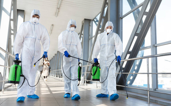 Медицинский персонал в защитной одежде дезинфицирует общественное место, подвергает риску пандемию здоровья