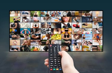 Bir el düz ekran televizyonun önünde siyah bir uzaktan kumanda tutuyor. Televizyon, fotoğraf çeken, egzersiz yapan insanlar gibi çeşitli aktiviteleri gösteren bir kolaj sergiliyor.