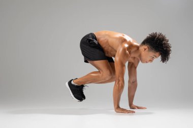 Formda bir genç adam atletik bir hareket yapar, güç ve çevikliğe odaklanır. Dinamik bir antrenmana hazırlanırken güçlü bir duruş sergiliyor. Kendini spora adadığını gösteriyor.