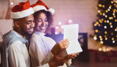 Xmas büyüsü. Noel ağacı önünde Noel Baba şapkası takan sevimli bir çift hediye kutusunu açıyor.