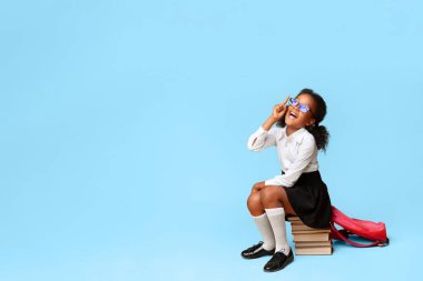 Afrikalı Liseli Kız 'ın sarı arka plan üzerinde oturan kitapları işaret eden bir fikri var. Boşluğu Kopyala, Stüdyo Çekimi