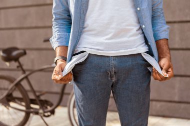 Yoksulluk ve para yokluğu. Tanımlanamayan afro bir adam boş ceplerini boşalttı, motosikletinin yanında duruyordu, kırpılmış görüntüsü vardı.