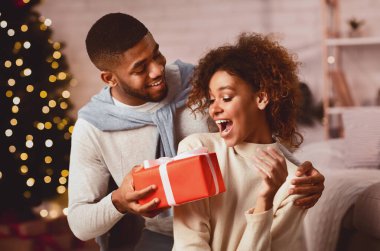 Xmas sürprizi. Afro adam kız arkadaşına Noel hediyesi veriyor, birlikte tatilleri kutluyor.