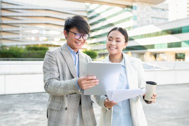İki genç Asyalı profesyonel, heyecan ve takım çalışmalarını gözler önüne sererek, kalabalık bir şehir ortamında belgeleri incelerken, ortak bir tartışmaya giriştiler.