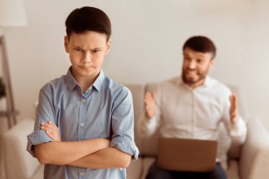 Kızgın baba, evdeki koltukta oturan dizüstü bilgisayarda çalışan rahatsız çocuğa bağırıyor. Seçici Odaklanma
