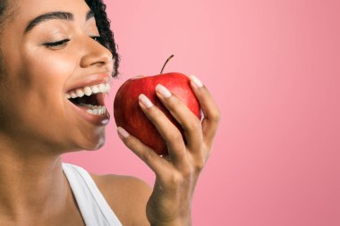 Stomatoloji Konsepti. Afro-Amerikan kadın kırmızı elma yiyor, sağlıklı dişler gösteriyor. Boşluğu kopyala