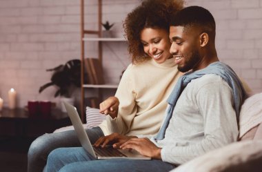 Mutlu afro eşler dizüstü bilgisayar kullanır, hafta sonunu evde geçirir ve film ararlar.