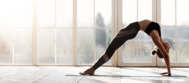 Akrobatik yogacı kız büyük panoramik pencerenin üzerinde köprü yapıyor, evde geriniyor, boş yer var.