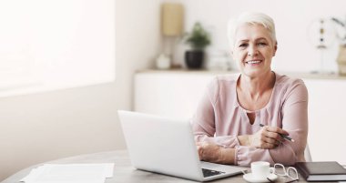 Evde dizüstü bilgisayarla çalışan mutlu büyükanne, boşluğu kopyala