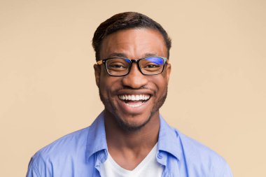 Milenyum boyunca gülümseyen, turuncu arka planda kameraya gülümseyen Afro adamın portresi. Stüdyo Çekimi