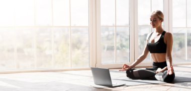 Spor başvurusu, web sitesi. Neşeli genç kadın evde yoga yapıyor, dizüstü bilgisayar kullanıyor, kopyalama alanı kullanıyor.