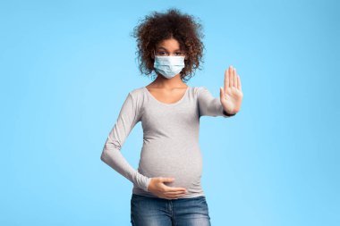 Bulaşıcı hastalıklar ve grip. Tıbbi maskeli hamile kadın dur işareti veriyor, gri arka plan