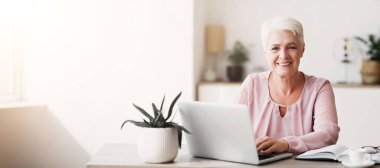 Evde dizüstü bilgisayarla çalışan mutlu iş kadını, kameraya gülümsüyor, boşluğu kopyalıyor.