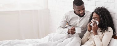 Şefkatli koca. Genç Afrikalı bir adam hasta karısına bakıyor, yatağına çay getiriyor.