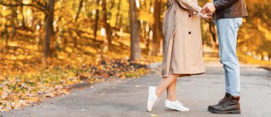 Altın orman yolunda sarılan iki aşığın kırpılmış görüntüsü.