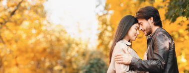 Romantik aşıklar birbirine alınlarıyla sarılır ve dokunurlar, sonbahar parkı arka planı, boş alanlı panorama