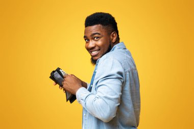 Yankesicilik konsepti. Çalıntı cüzdan taşıyan siyah bir hırsız ve sarı stüdyo geçmişinde para sayan bir hırsız.