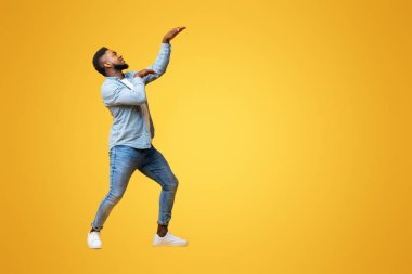 Komik Afrikalı Amerikalı adam Mısır tarzında dans ediyor ve eğleniyor sarı stüdyo arka planında, boşluğu kopyala