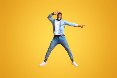 İnanılmaz bir teklif. Duygusal afro adam zıplıyor ve el ve sarı arka planla fotokopi alanını işaret ediyor.