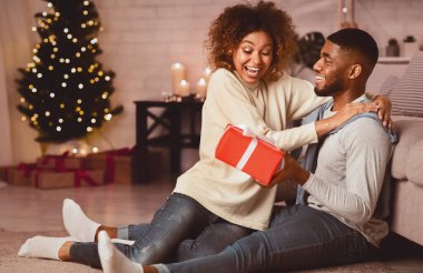 Yakışıklı afro adam Noel hediyesi ile sürpriz kız, rahat bir odada dinleniyor.