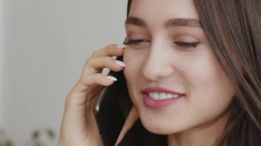Görüşmeyeli uzun zaman oldu. Evde cep telefonuyla konuşan mutlu genç kadın, kapat.