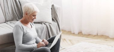 Evde dizüstü bilgisayarla oturmuş pazarlama raporlarını, boş alanı kontrol eden yaşlı bir girişimci.