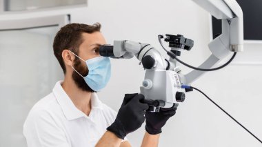 Diş tedavisinde modern teknolojileri kullanan yüksek nitelikli sakallı erkek dişçi. Stomatolojide karmaşık vakalar.