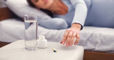 Hamilelik. Tanımlanamayan hamile bir kadın ilaç alıyor ve yatak odasında uzanıyor. Kırpılmış, Panorama, Seçici Odaklanma