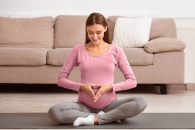 Beklenti Konsepti. Karnına kalp işareti yapan mutlu hamile kadının dikey görüntüsü.