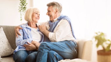 Kıdemli sevecen çift rahatlatıcı ve evde kanepeüzerinde birbirlerine bakıyor
