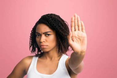 Kes şunu. Ciddi siyahi kadın portresi. Elini uzatmış, beyaz duvarın üzerinden izole edilmiş dur işareti yapıyor.