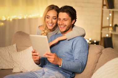 Mutlu çift tablette video görüşmesi yapıyor, kış akşamını evde geçiriyorlar.