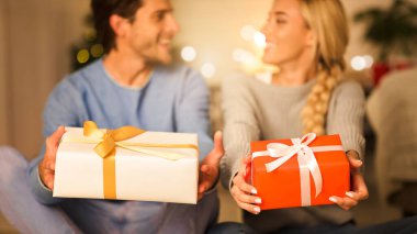 Mutlu çift hediye kutularını tutuyor ve onları rahat bir odada kameraya doğru geriyor.
