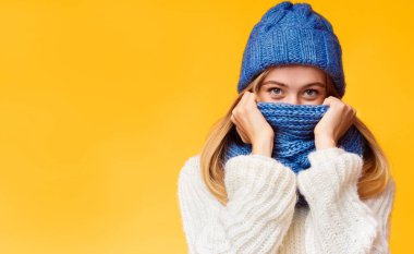 Kış soğuğundan saklanan esrarengiz sarışın kız pembe arka planda, yüzünü eşarpla örten, serbest alan