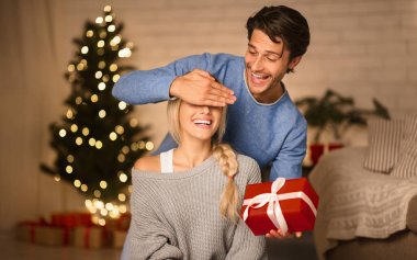 Genç çift Noel arifesinde hediyelerini değiştiriyor. Adam sevgilisine Noel hediyesi veriyor, gözlerini kapatıyor.