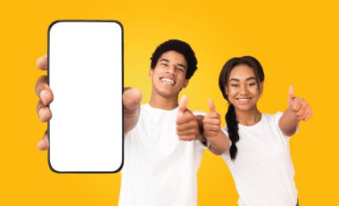 Genç bir siyah adam ve kadın ellerinde boş ekranlı bir akıllı telefon tutuyorlar. İkisi de gülümsüyor ve başparmak işareti yapıyor. Arkaplan koyu sarı renktedir..