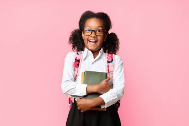 Birinci sınıftaki heyecanlı afro kız elinde sarı stüdyo geçmişiyle ilgili kitaplar tutuyor. Boşluğu kopyala