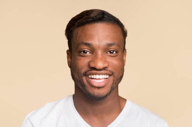 Sarı arka planda duran kameraya gülümseyen siyah adamın portresi. Stüdyo Çekimi