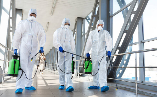 Медицинский персонал в защитной одежде дезинфицирует общественное место, подвергает риску пандемию здоровья