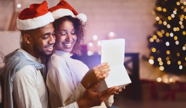 Xmas büyüsü. Noel ağacı önünde Noel Baba şapkası takan sevimli bir çift hediye kutusunu açıyor.