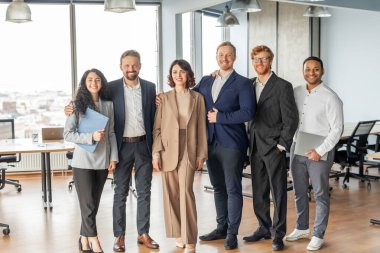 Modern bir ofis ortamında altı farklı iş adamından oluşan bir grup bir arada duruyor. Hepsi gülümsüyor ve iyi bir ruh hali içinde görünüyorlar. Takım iki kadın ve dört erkekten oluşuyor.