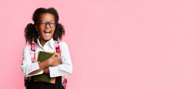 Heyecanlı Afro İlköğretim Öğrencisi Kız Sarı Stüdyo Arkaplanı Üzerinde Kameraya Göz Kırpıyor. Okula Dönüş Konsepti. Boş Alan