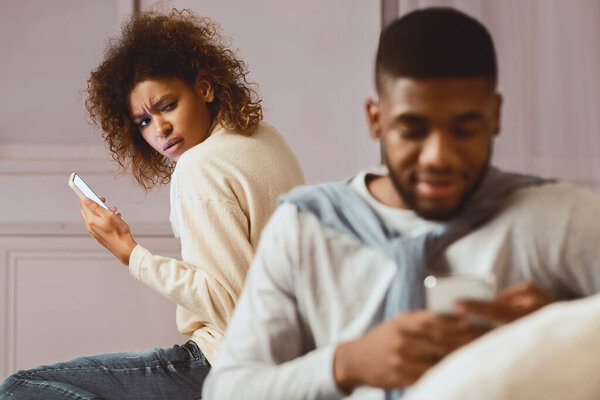 Jealousy. Woman suspecting husband cheating on her, texting on phone