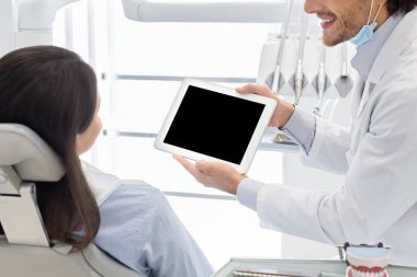 Hasta boş dijital tablet ekranını, stomatolojide modern teknolojileri, boş alanı gösteren dişçinin kırpılmış görüntüsü