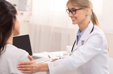 Ziyaretçi hekim. Gülümseyen Doktor Kadın Hasta 'yı muayenehanesinde rahatlatıyor. Seçici Odaklanma