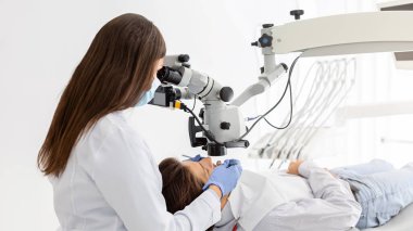 Diş tedavisinde modern teknolojileri kullanan profesyonel kadın dişçinin yan görünüşü