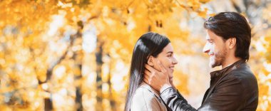 Yakışıklı bir adam, kadın yüzüne dokunuyor, aşk sözleri söylüyor, sonbahar ormanı geçmişi.