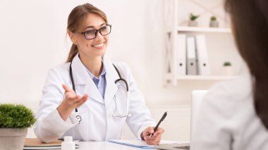 Ziyaretçi Doktor. Ofisinde oturan tanınmayan bir hastayla konuşan gülümseyen terapist kadın. Seçici Odaklanma