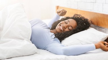 Genç, mutlu, uyuyan Afrikalı kadın yatakta uzanıyor, boş alan, panorama.